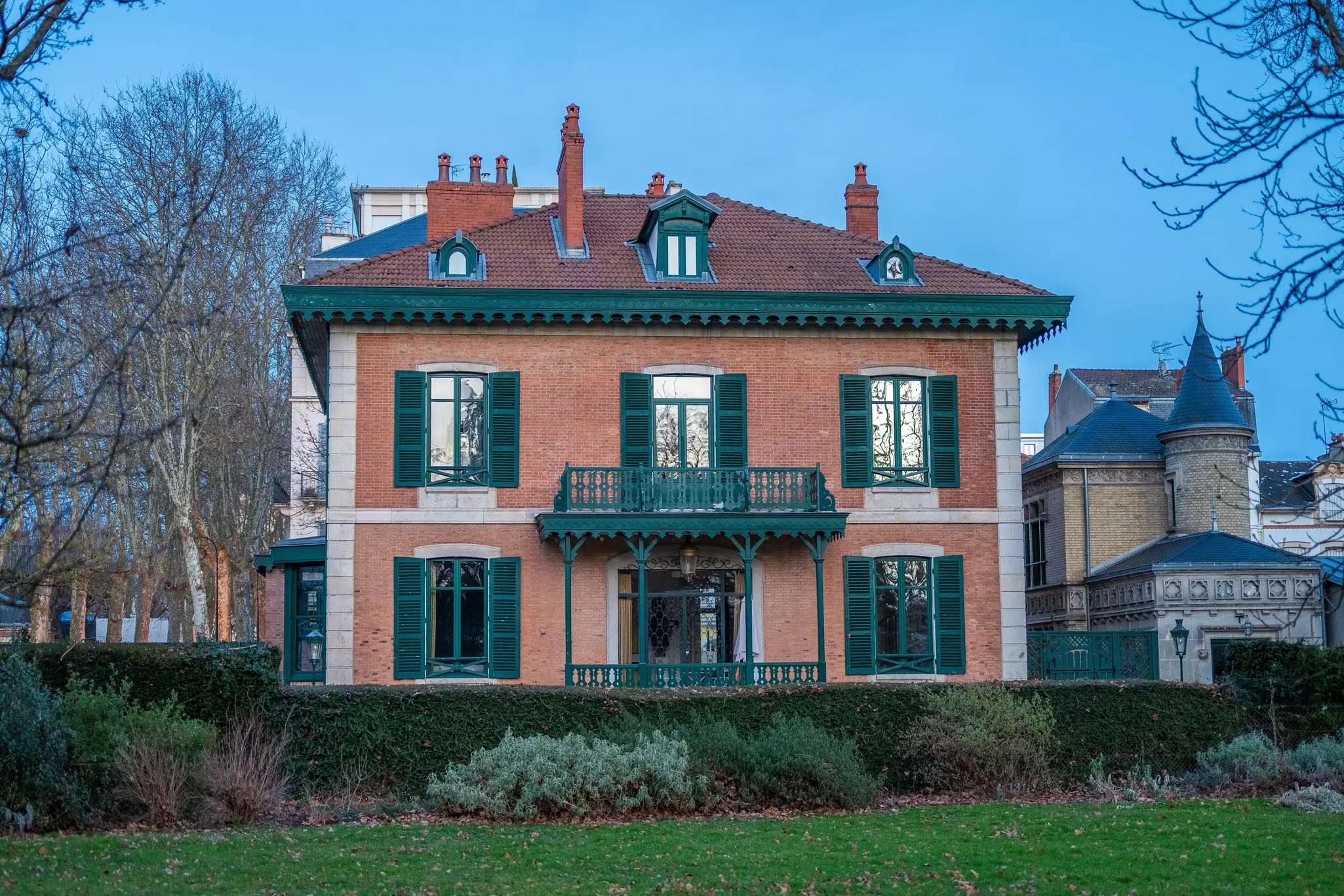 A large red-brick mansion with grand shuttered windows