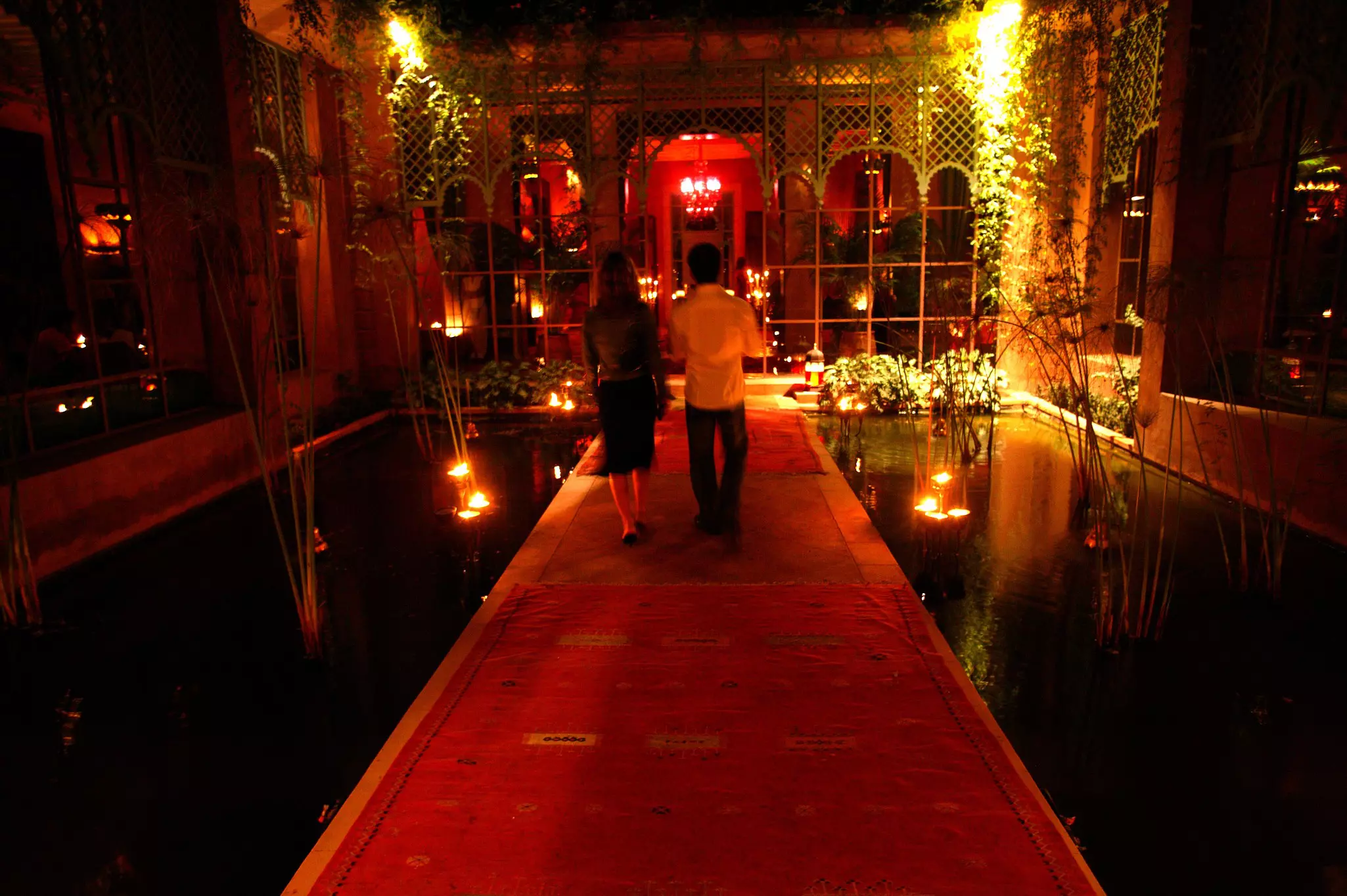 Two people walking on a carpet runner through the darkened entrance of a restaurant