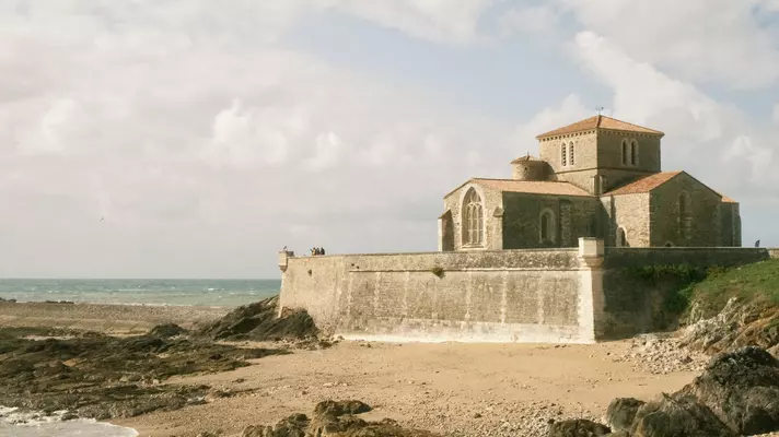 People standing outside Marché de la Chaume. Prieuré Saint-Nicolas near the water