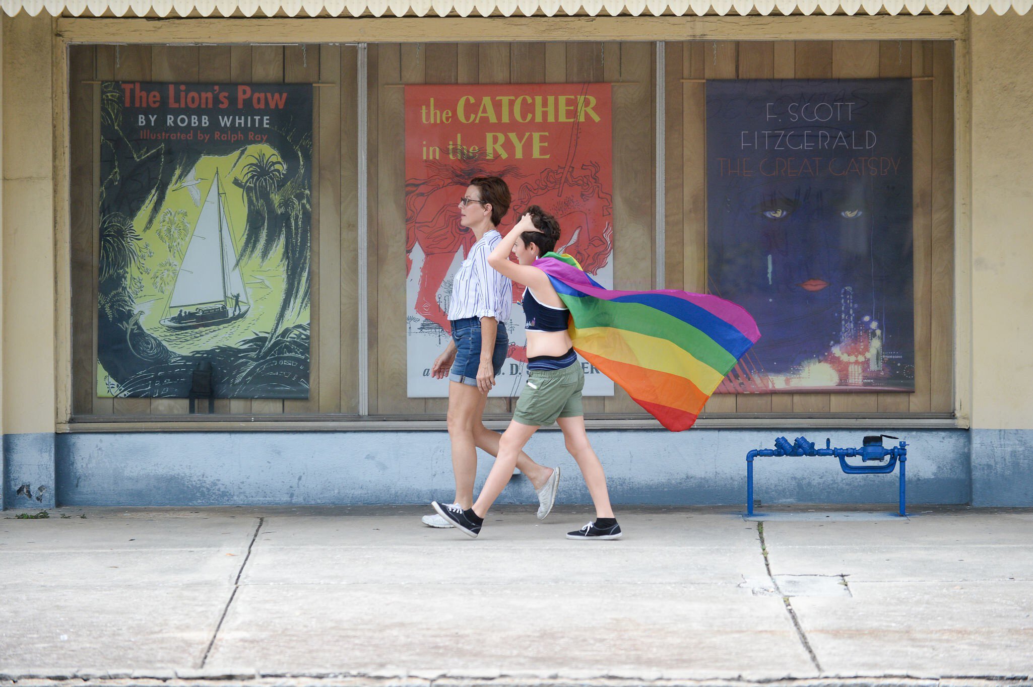 July 24, 2018: Two women walking along the sidewalk, one with a pride flag, during St. Pete Pride.