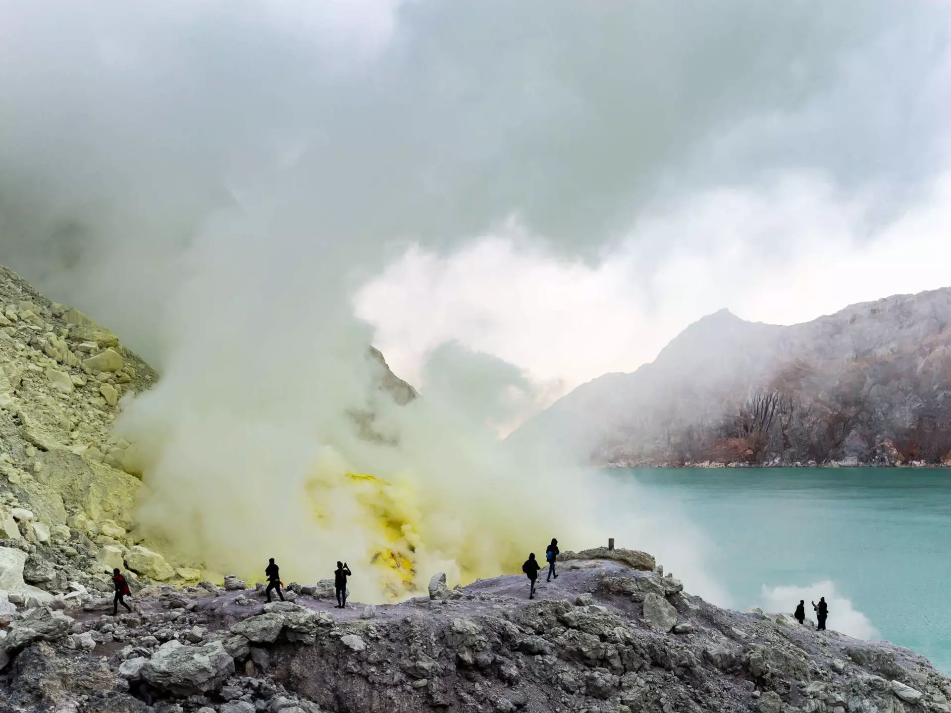 Tourists walking to see the sulfur mines and blue green lakes in Ijen crater, Indonesia