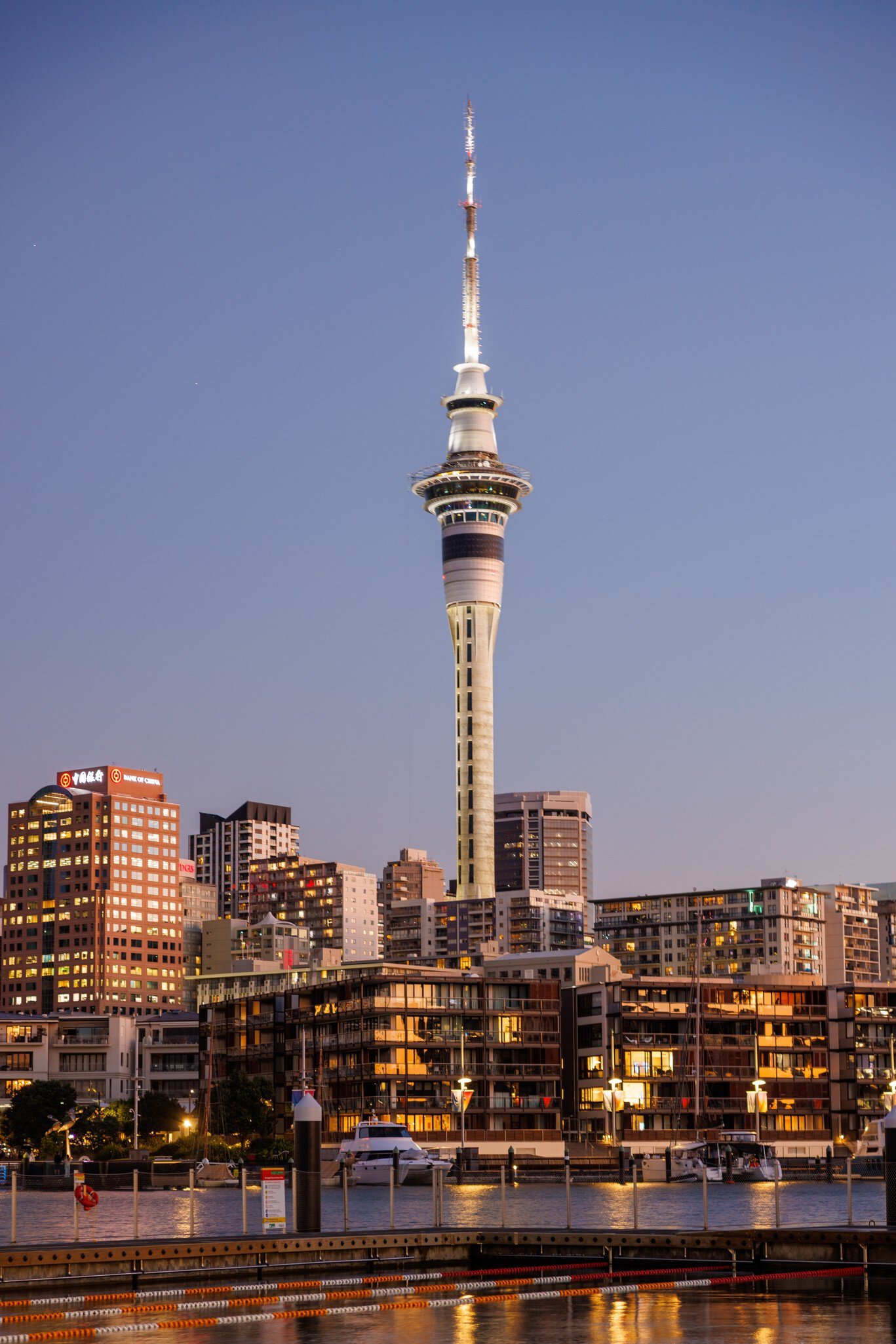 View of the Sky Tower and waterfront in Auckland, New Zealand, at night.