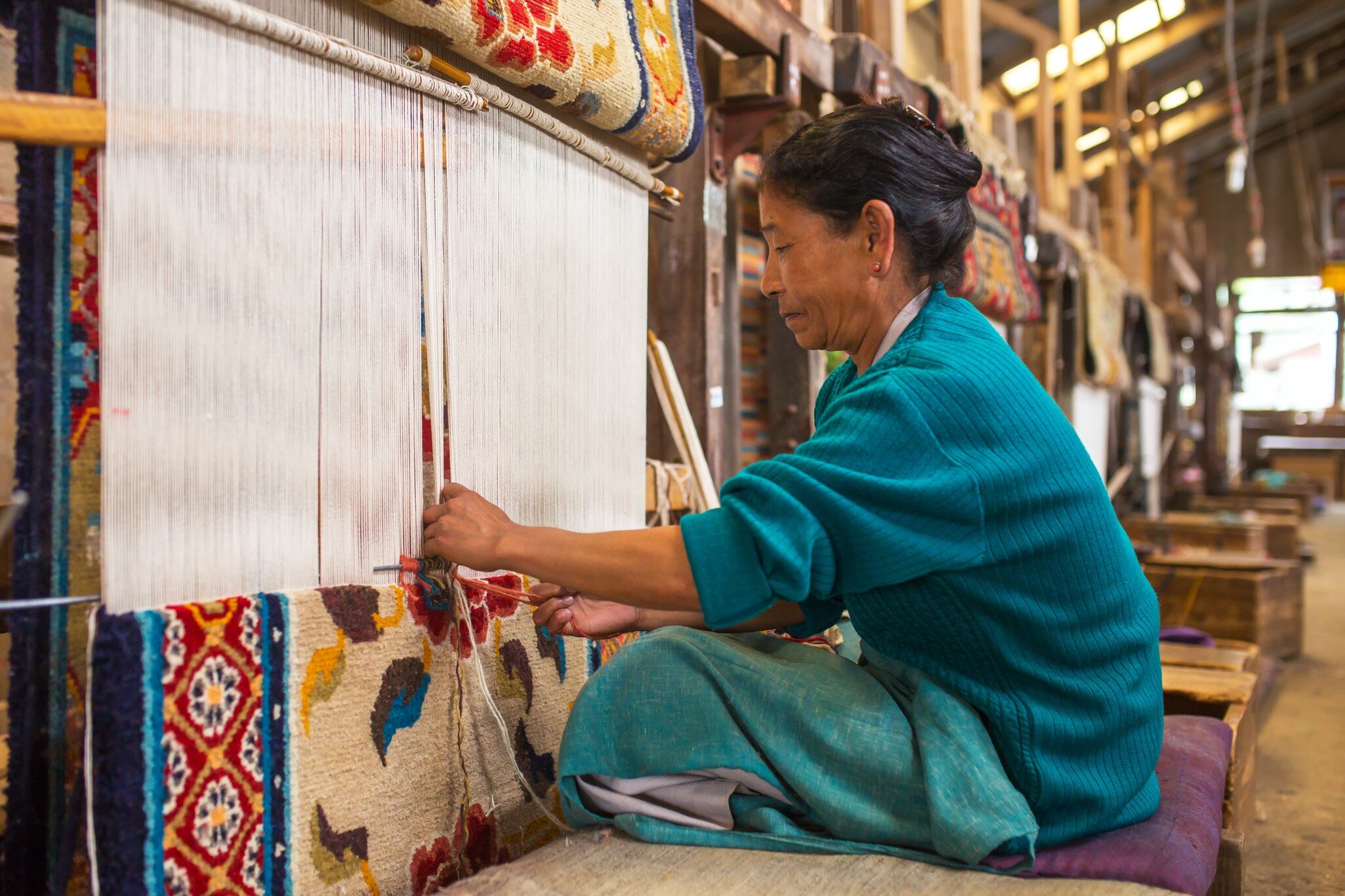 Tibetan woman works as a weaver in the carpet workshop of Tibetan Refugee Self Help Center, Darjeeling, India.