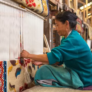 Tibetan woman works as a weaver in the carpet workshop of Tibetan Refugee Self Help Center, Darjeeling, India.