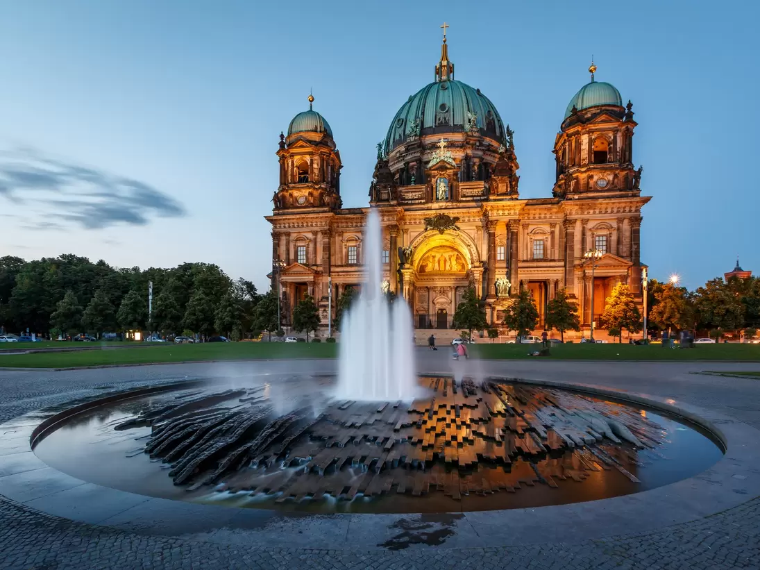 Berlin Cathedral (Berliner Dom) and fountain illuminated at dusk.