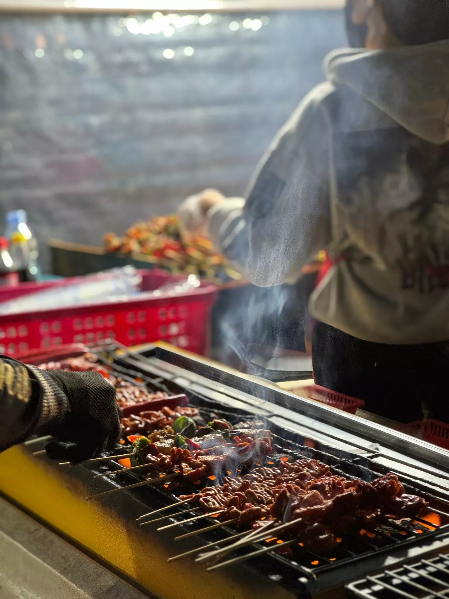 A chef preparing meat skewers over a grill.