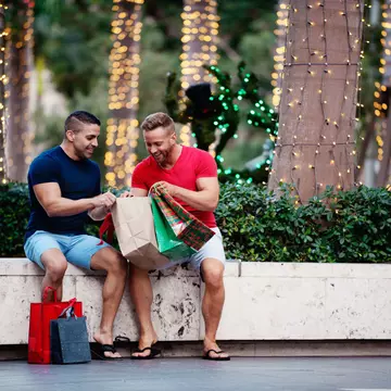 A gay couple with shopping bags, sitting outside and looking at their purchases