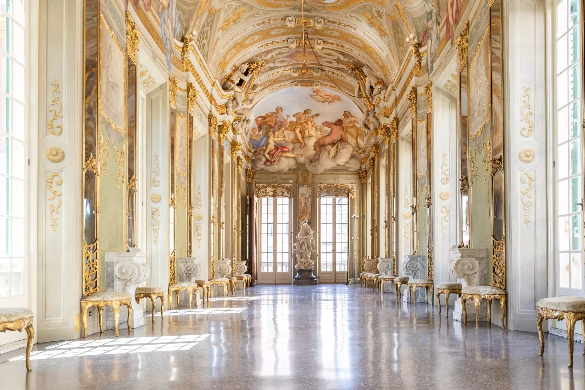 A room in a palace decorated with marble, mirrors and gold-trimmed furniture.