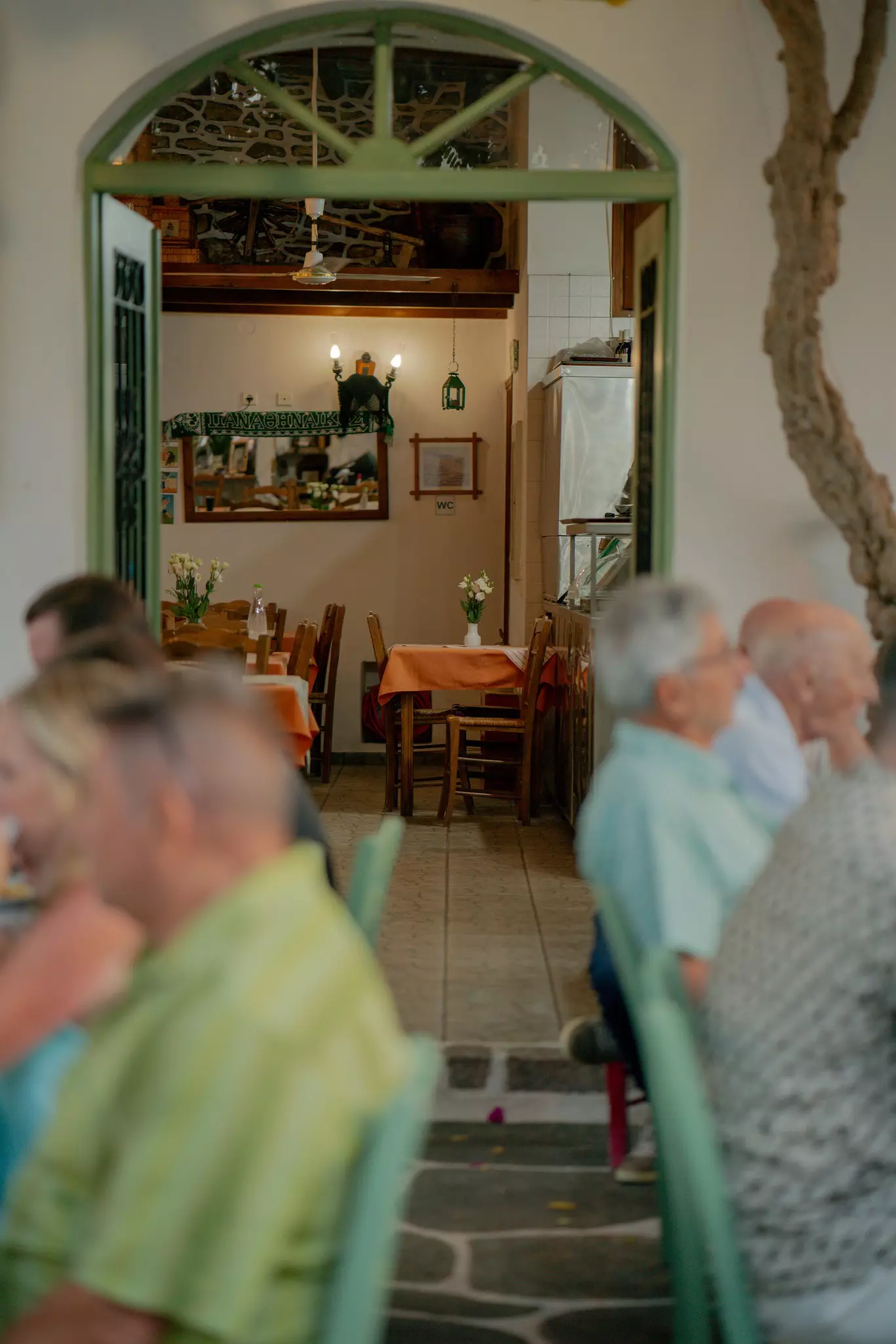 Diners on an outdoor patio; the empty indoor dining room is visible through a doorway.