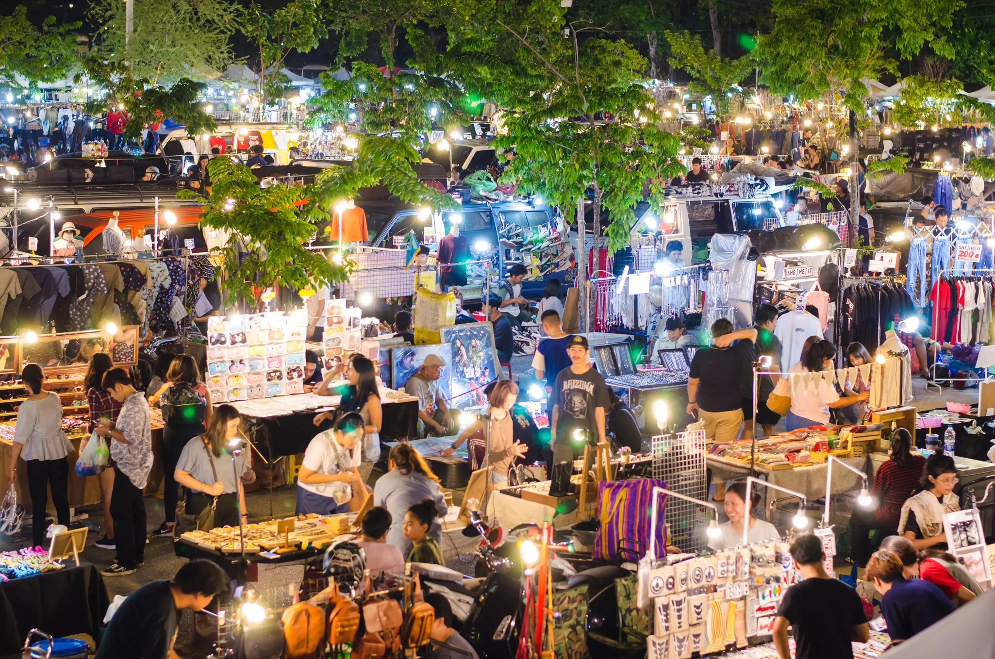 A busy night market with shoppers browsing a range of stalls packed closely together in the open air.