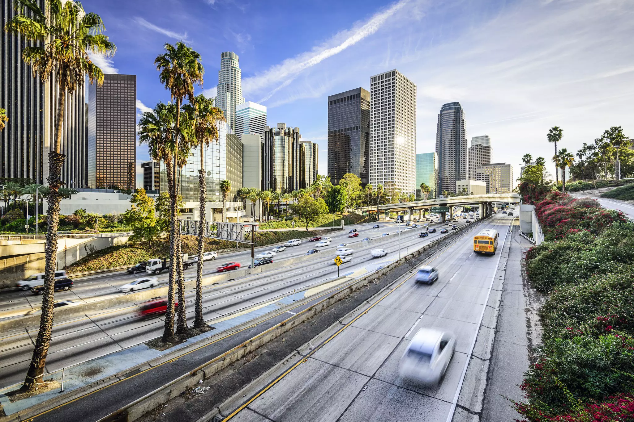 A highway, near the high-rise buildings of a city downtown, with cars zipping along it.