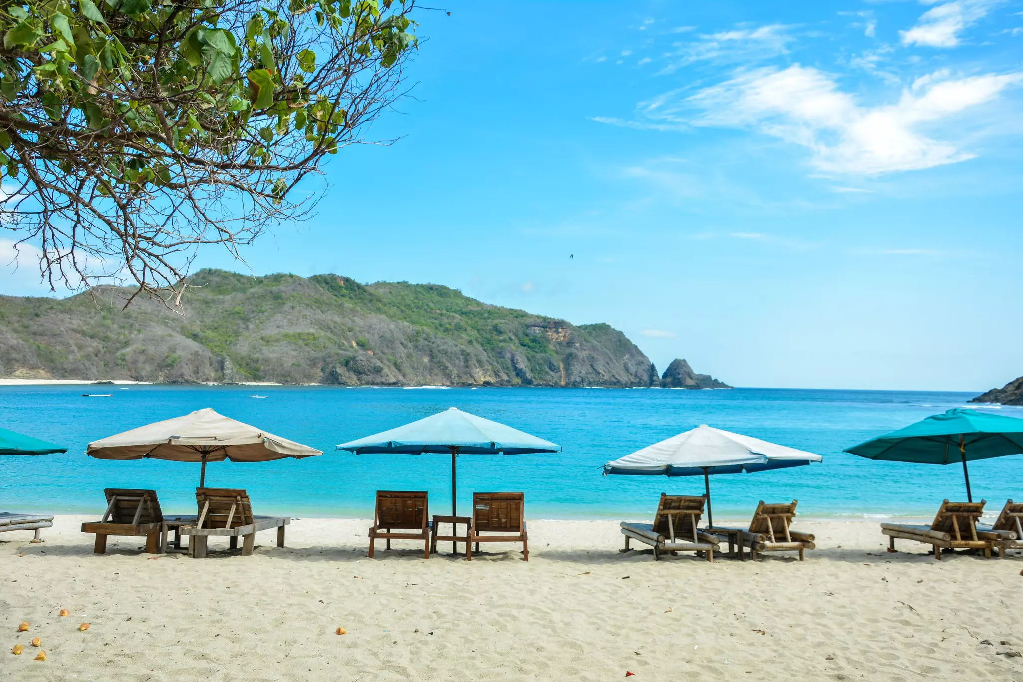 A row of sunloungers and umbrellas on Mawun Beach in Lombok.