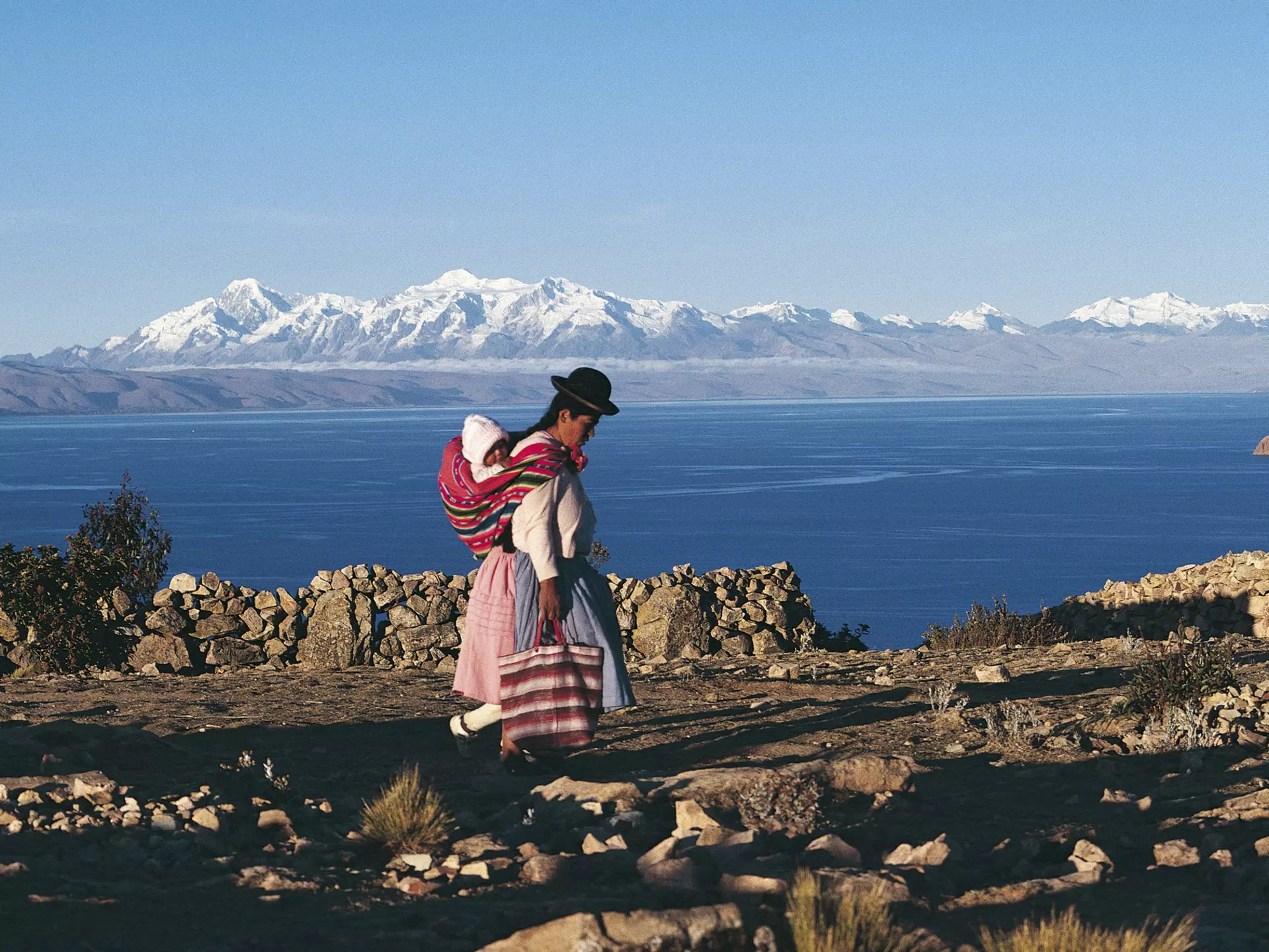 A Bolivian woman walking in front of Lake Titicaca
521862542
mother:CB2, two people:CB1, traditional clothing:CB2, women:CB2, side view:CB1, Bolivian:CB2, island:CB2, lakeshore:CB2, baby carrier:CB2, bag:CB2, landforms:CB2, snow:CB2, infant:CB2, mountain range:CB2, wall:CB2, Isla del Sol:CB2