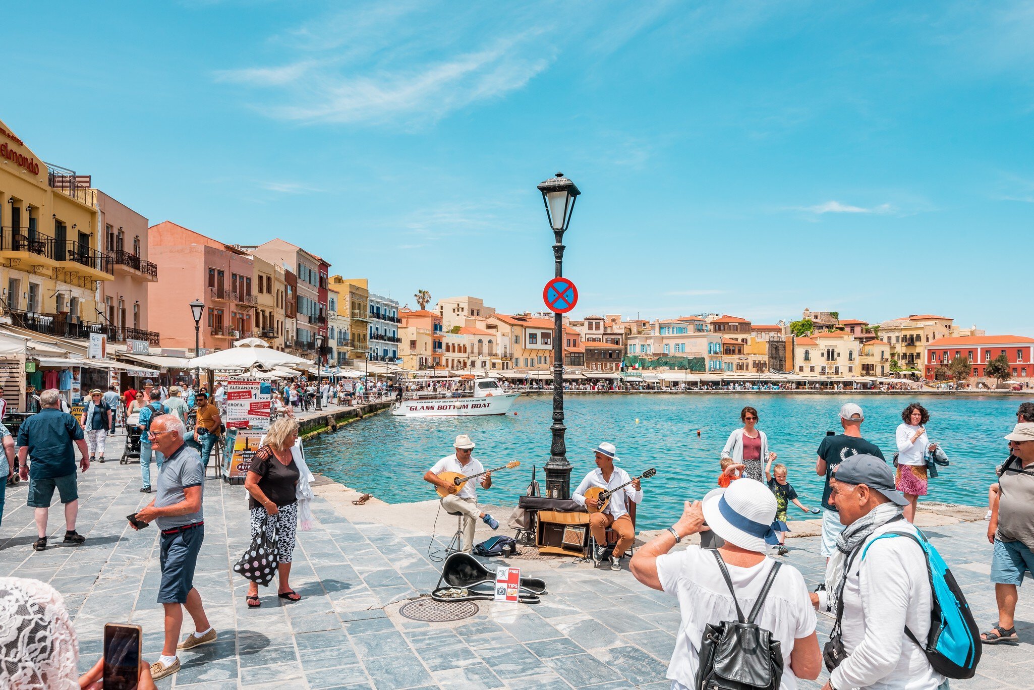View of the Venetian harbor in Chania, Crete, on a sunny day surrounded by colorful old houses and the water.