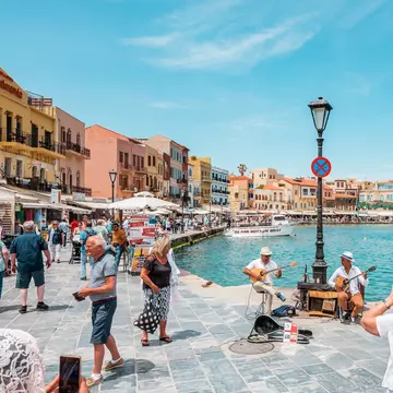 View of the Venetian harbor in Chania, Crete, on a sunny day surrounded by colorful old houses and the water.