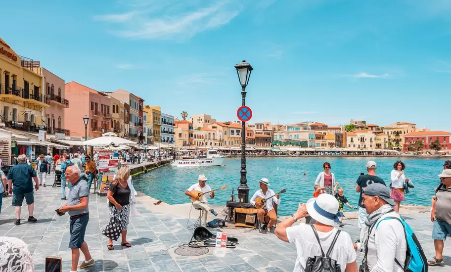 View of the Venetian harbor in Chania, Crete, on a sunny day surrounded by colorful old houses and the water.