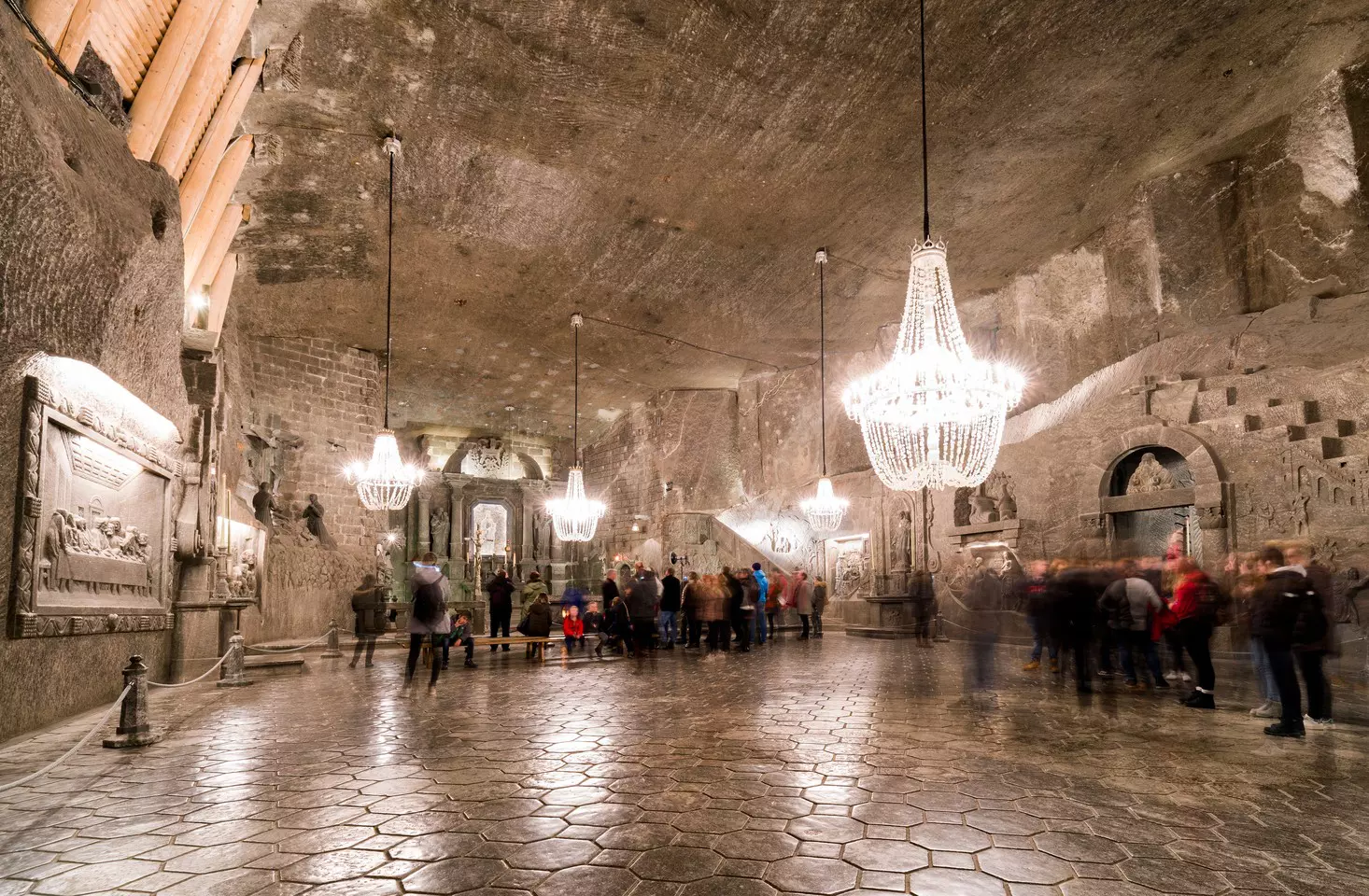 The main chamber in a large salt mine, with chandeliers hanging from the ceiling and people moving around.