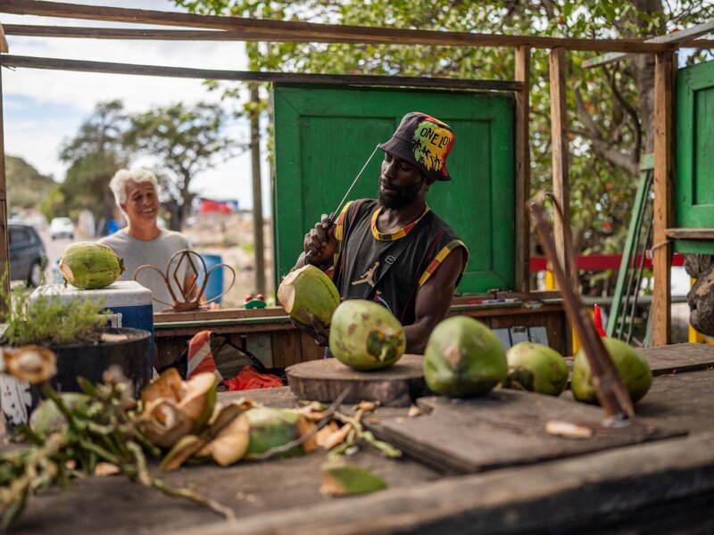 MONTSERRAT. CARIBBEAN. FEBRUARY 2026. Ackime Meade can be found everyday, along Carr’s Bay Beach on Monserrat, preparing and serving fresh coconut to locals and tourists alike, looking for a refreshing drink and snack down by the water.