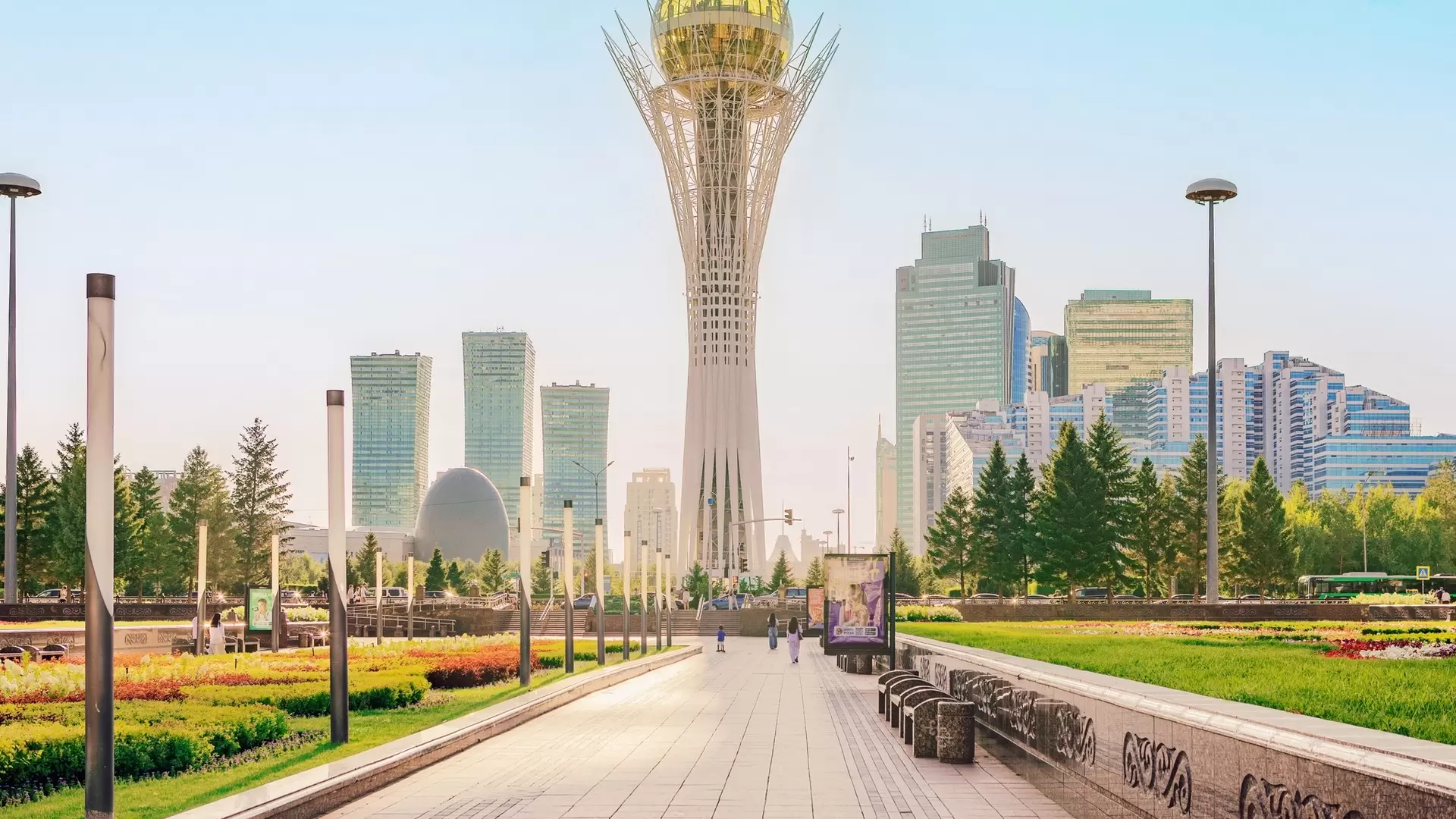 Astana, Kazakhstan – July 17, 2025: The iconic Bayterek Tower stands tall amidst the modern skyline and lush green park of Astana, Kazakhstan. A sunny day view of the city's urban landscape.