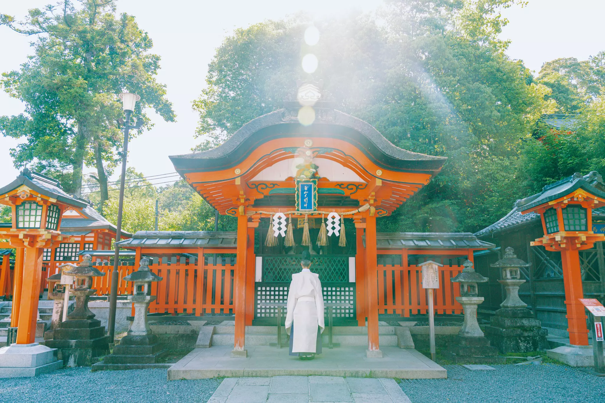 Orange Japanese architecture frame a man in a white robe.
