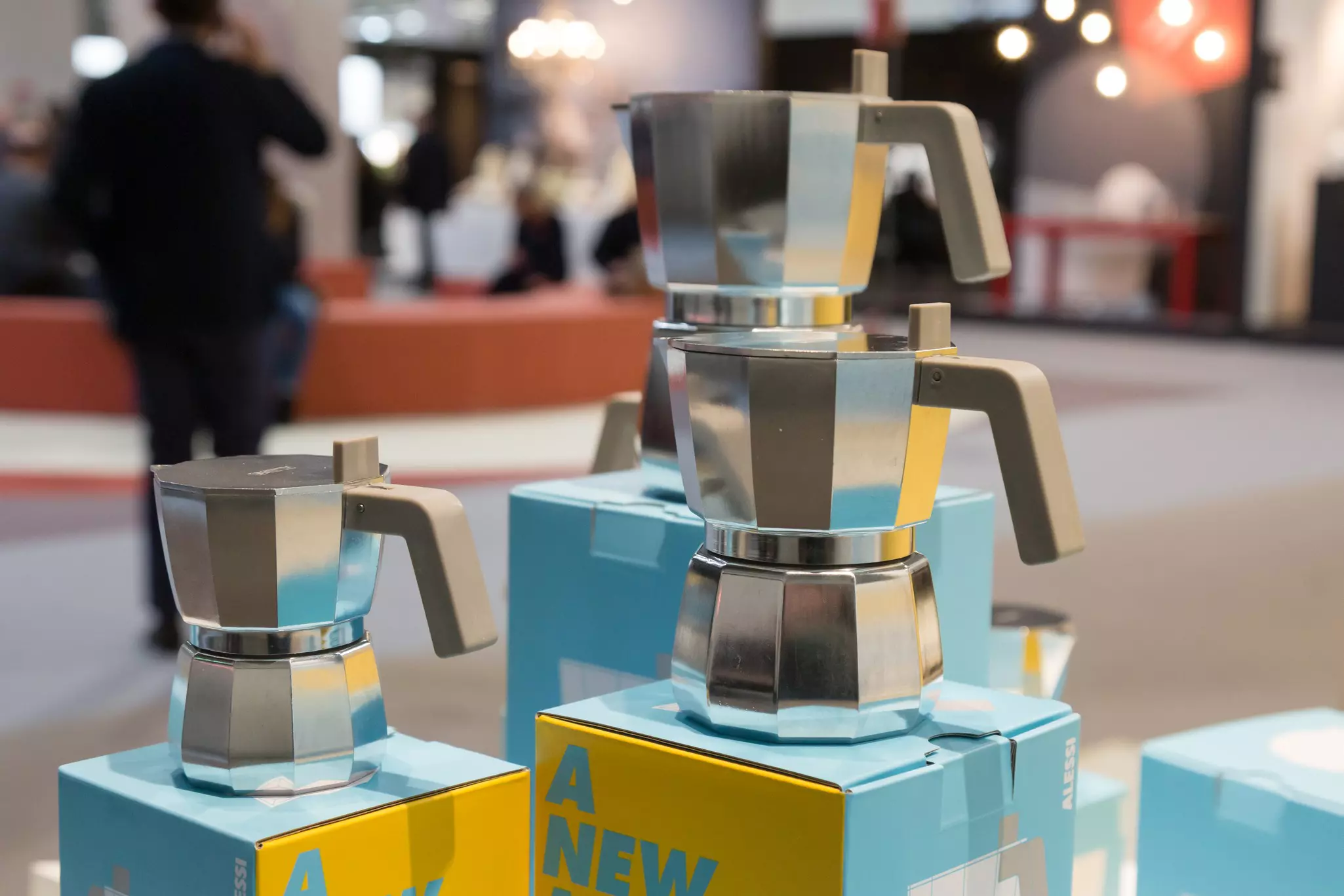 A woman sits on a wooden bench in a small room and looks through a small glass window into where a prisoner would be sitting when meeting his family.
