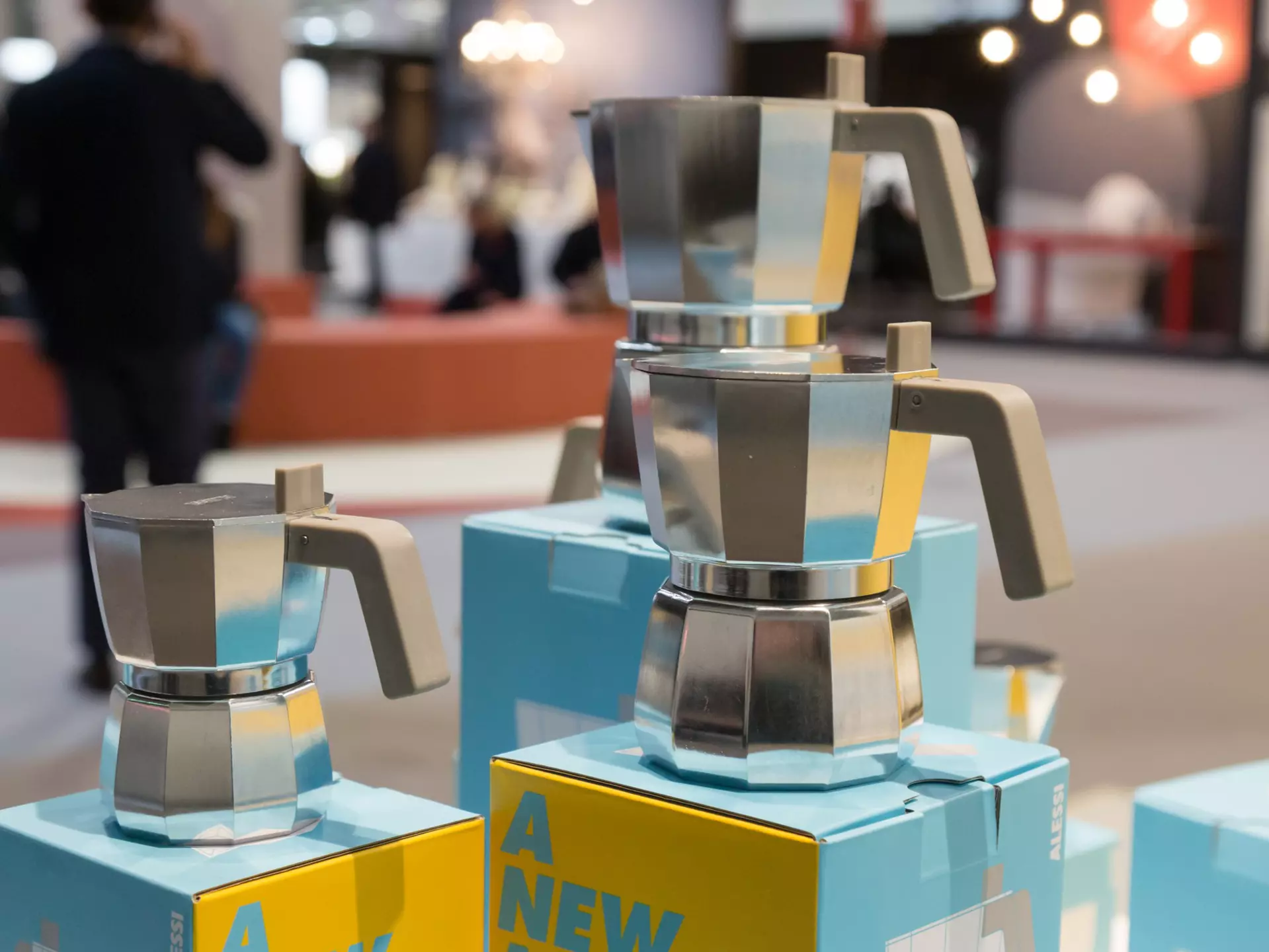 A woman sits on a wooden bench in a small room and looks through a small glass window into where a prisoner would be sitting when meeting his family.