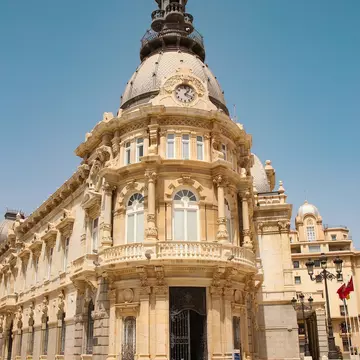 Town Hall under a cloud dappled blue sky with palm trees and roses, Cartagena, Murcia Region, Spain, Europe