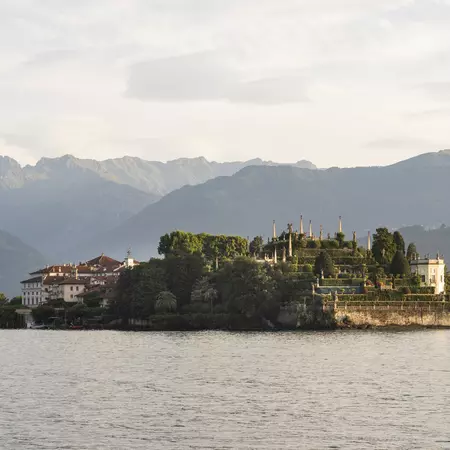 A distant island with a palace and tiered gardens sits in a lake, without mountains in the background. 