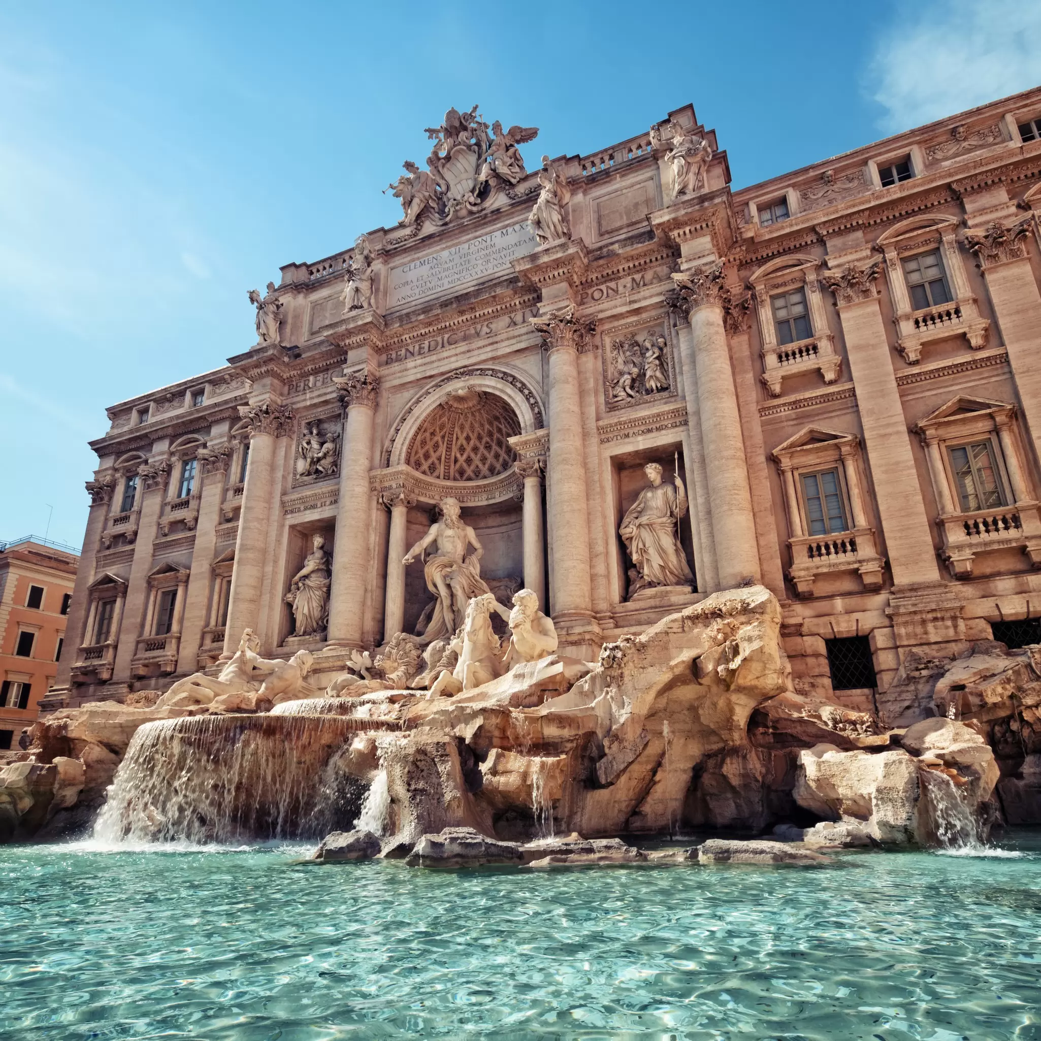 A marble fountain with elaborate carvings above a pool of blue water.