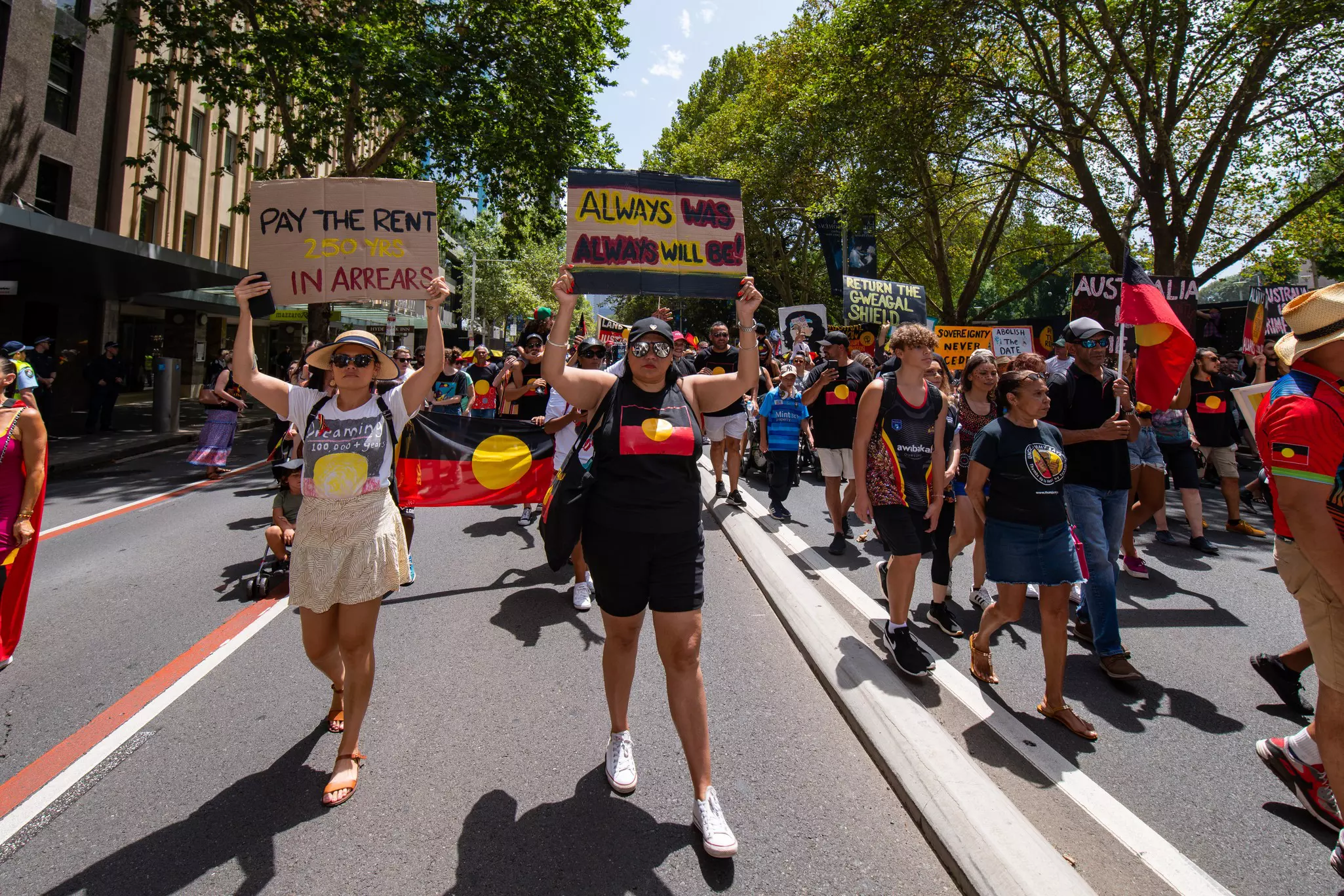Protestors hold flag and placards during a demonstration in a city street.