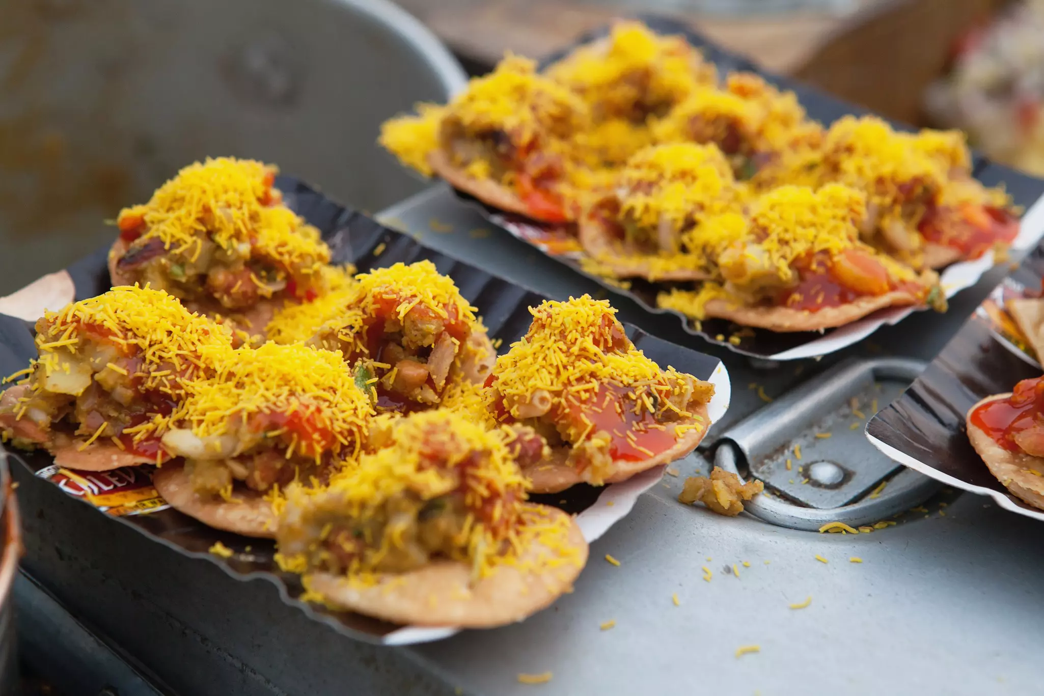 A view of dishes of street food: vegetables on kachoris sprinkled with a rice topping