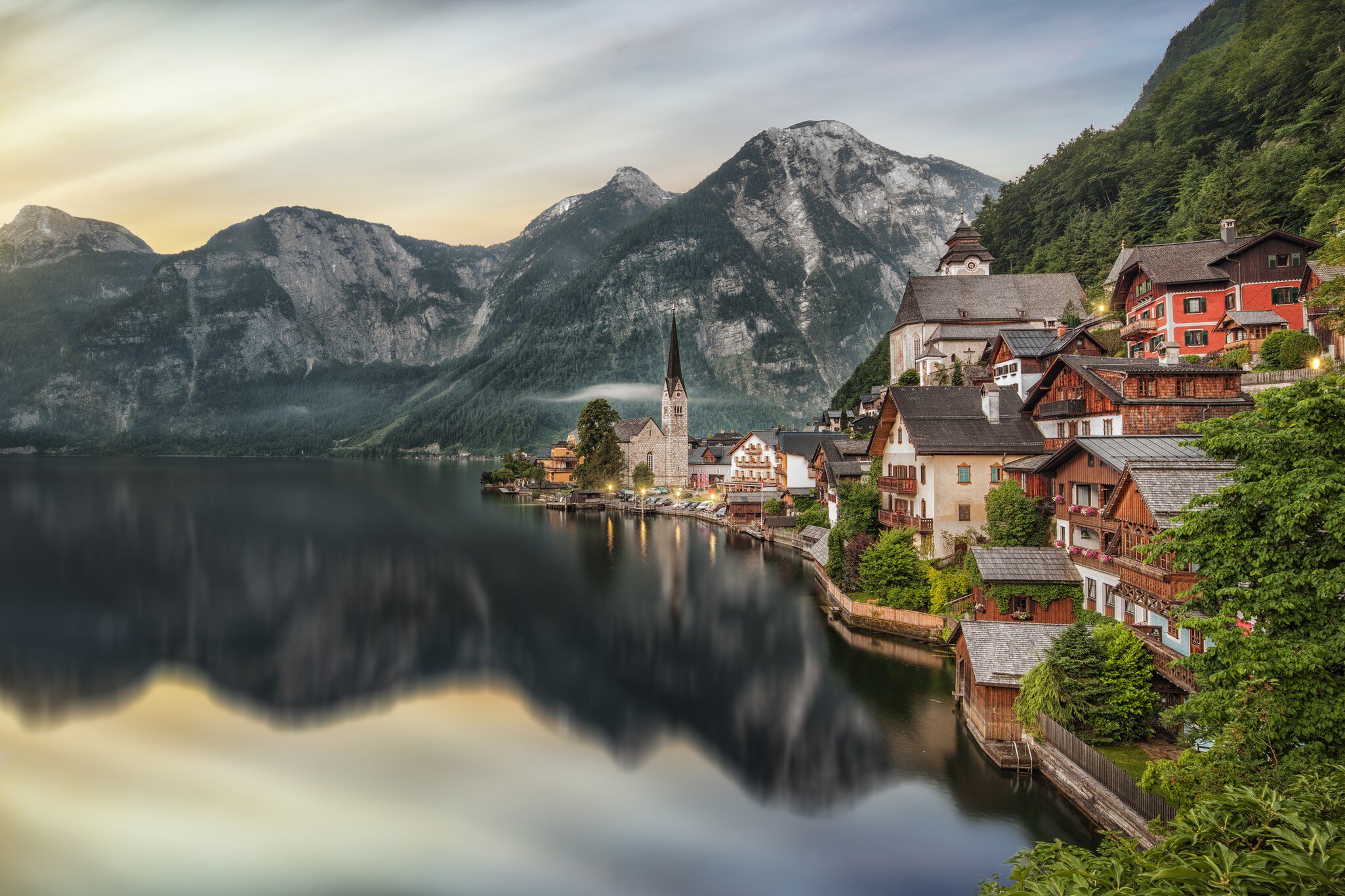 Mountains are seen in the background as a girl and a boy are semi-submerged as they jump into the water of Zell am See, Salzburgerland, Austria