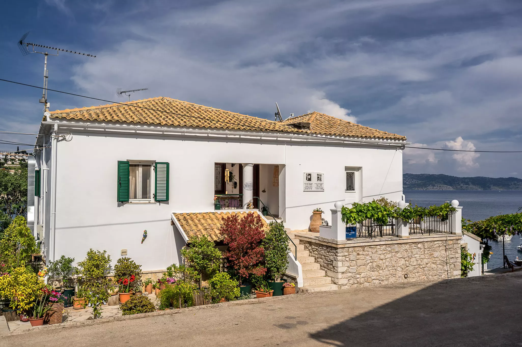 A white building with yellow roof and flowers in pots in front