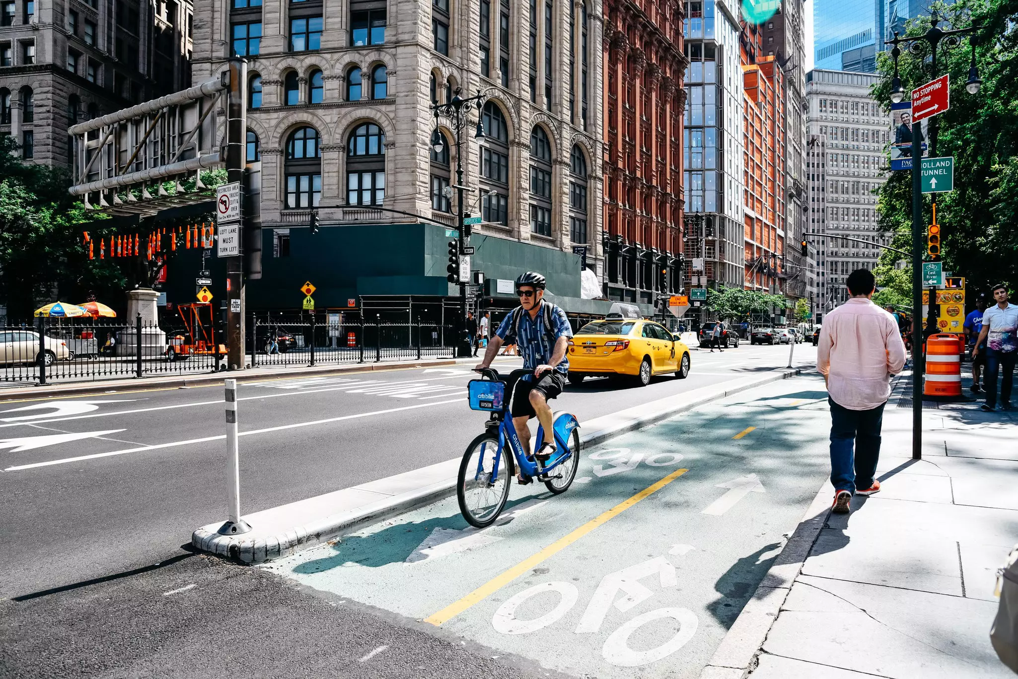 Helmeted cyclist riding in a bike lane on a blue Citi Bike in Manhattan