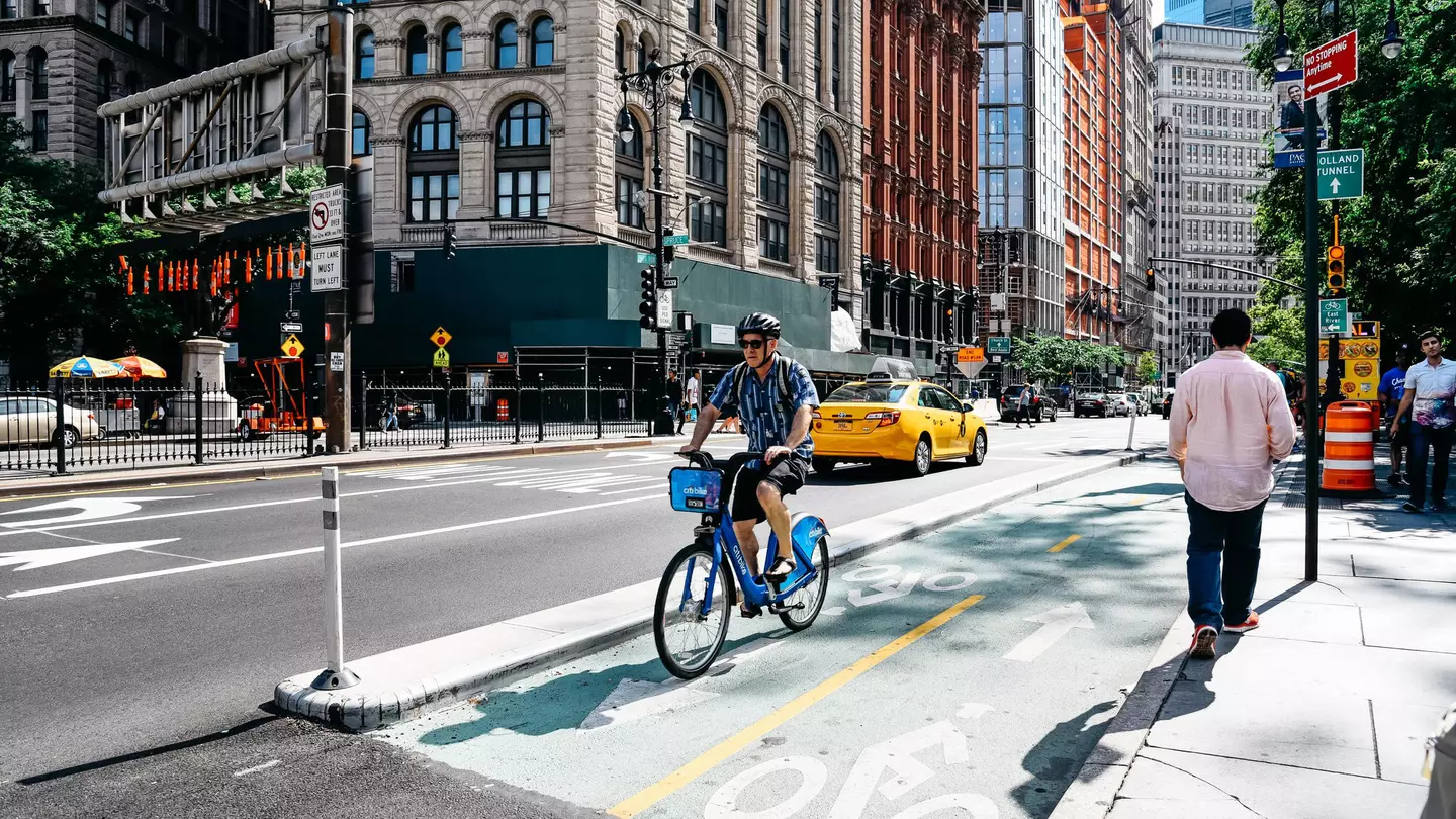 Helmeted cyclist riding in a bike lane on a blue Citi Bike in Manhattan