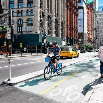 Helmeted cyclist riding in a bike lane on a blue Citi Bike in Manhattan