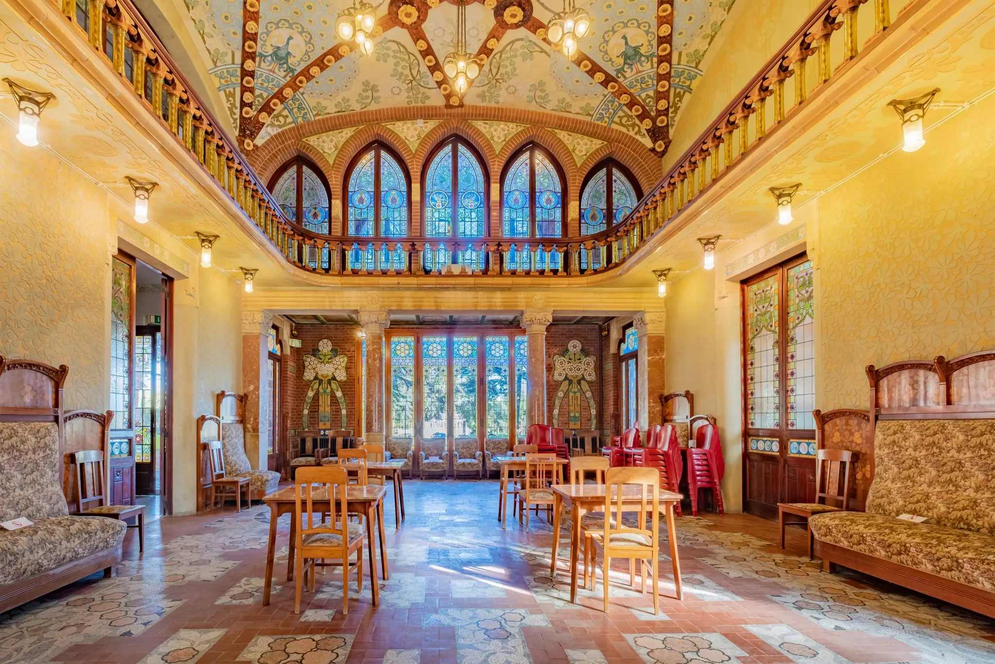 A large room inside a psychiatric hospital, with large stained-glass windows and beautiful mosaics decorating the ceiling.