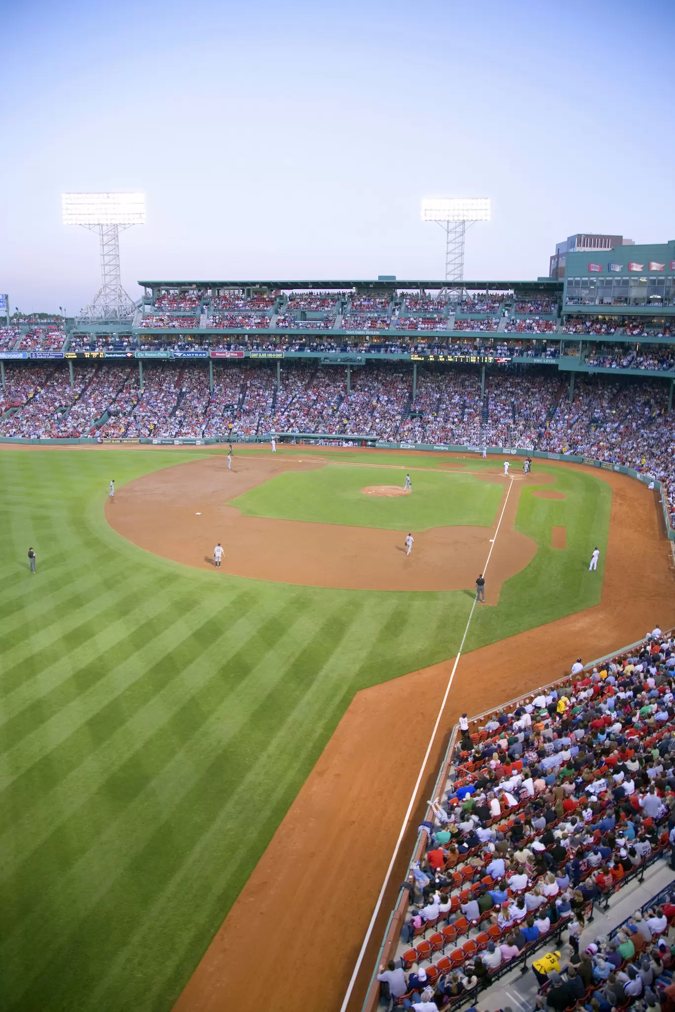 A packed baseball stadium with fans sat in tiered seats watching the action on the pitch below