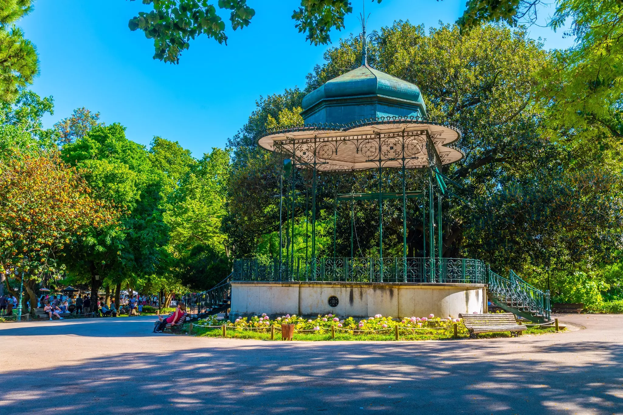 An ornate wrought-iron bandstand in parkland.