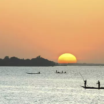African fishermen silhouetted in canoes at sunset