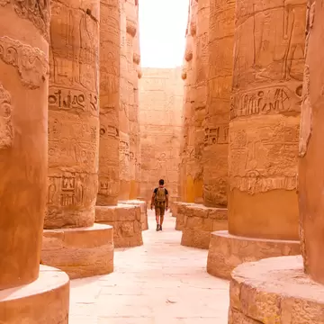 A lone man walking through enormous, free-standing stone carvings.