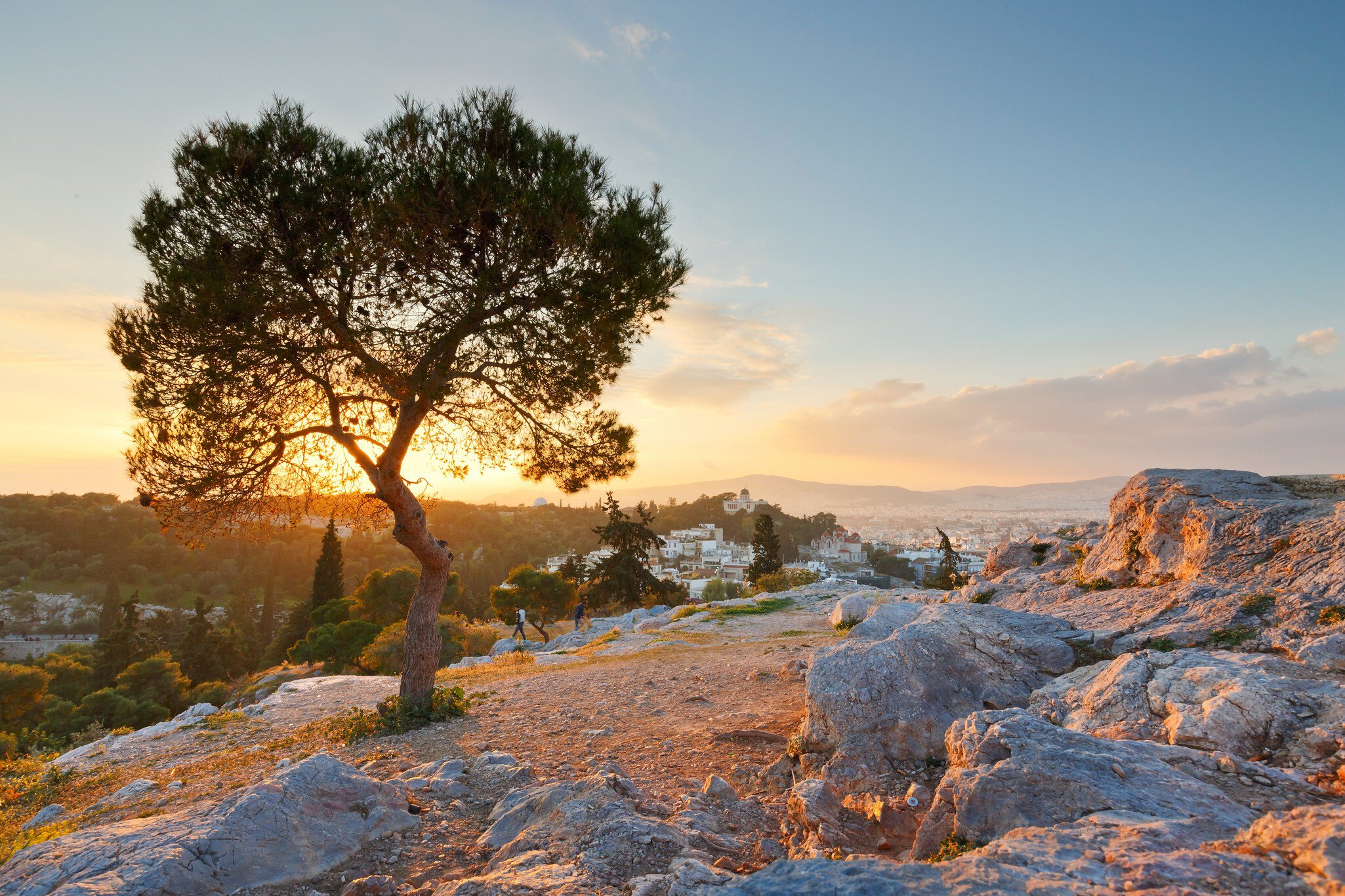 View of Thissio dominated by the National Observatory from Areopagus hill as the sun sets over the horizon in the background in Athens, Greece.