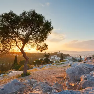 View of Thissio dominated by the National Observatory from Areopagus hill as the sun sets over the horizon in the background in Athens, Greece.
