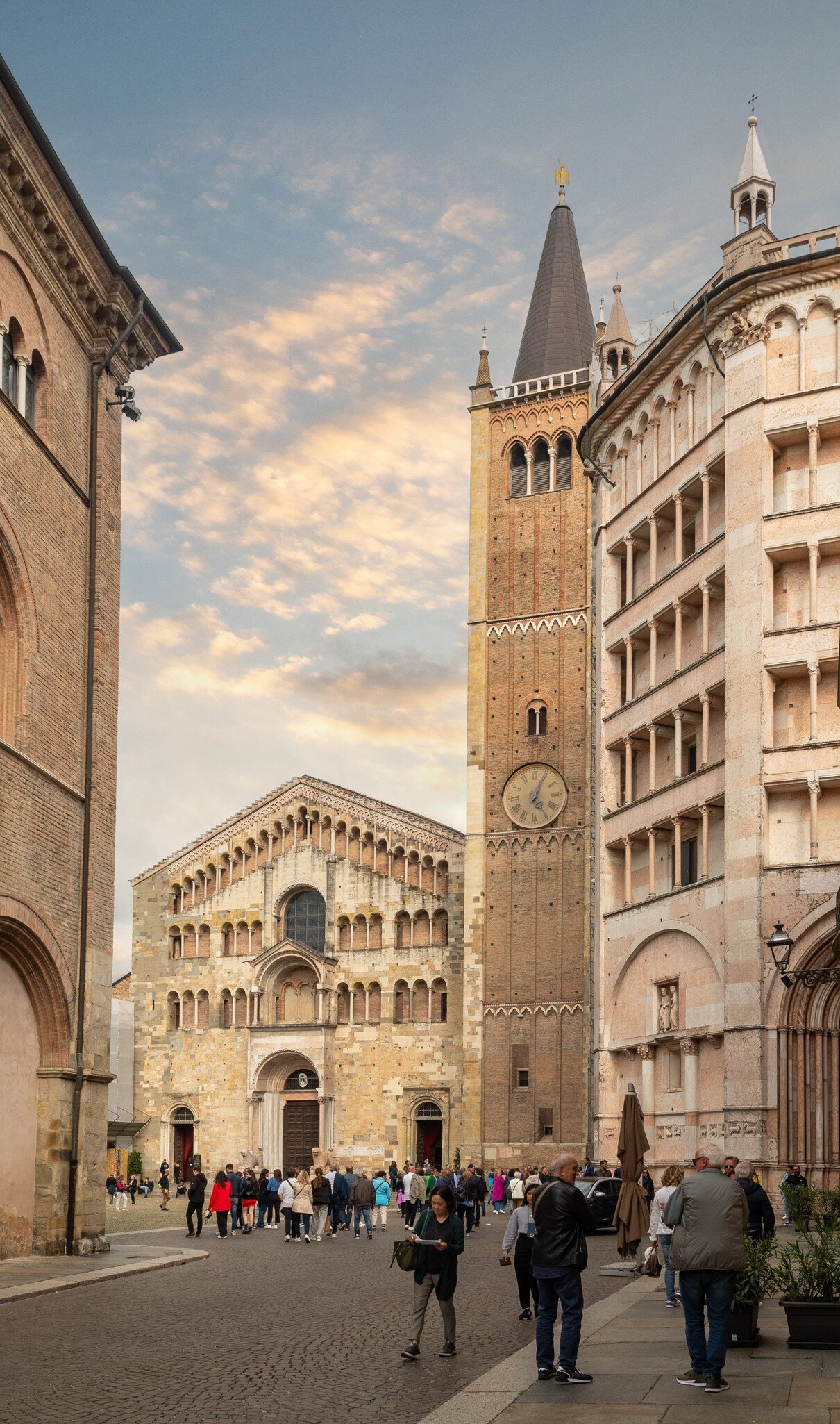 Crowds of tourists outside the Parma Cathedral next to the bell tower and the octagonal Baptistery.