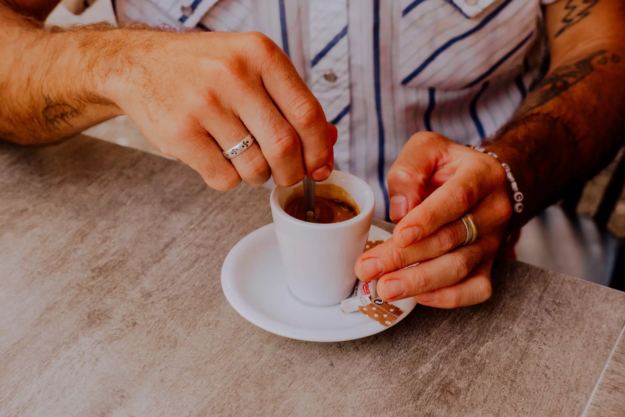 A hand stirring a small cup of espresso. 
