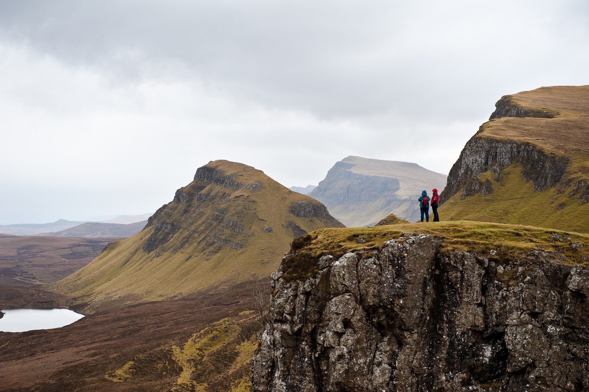 Two people hiking the Quairing Mountains on the Isle of Skye in Scotland.