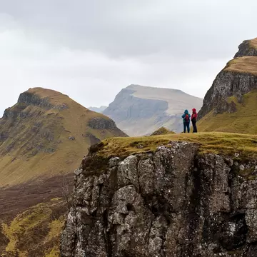 Two people hiking the Quairing Mountains on the Isle of Skye in Scotland.