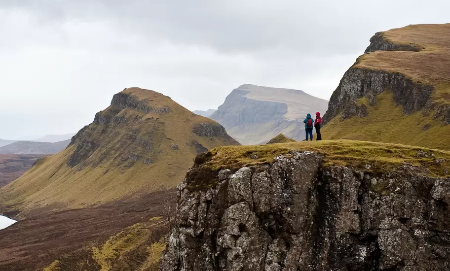 Two people hiking the Quairing Mountains on the Isle of Skye in Scotland.