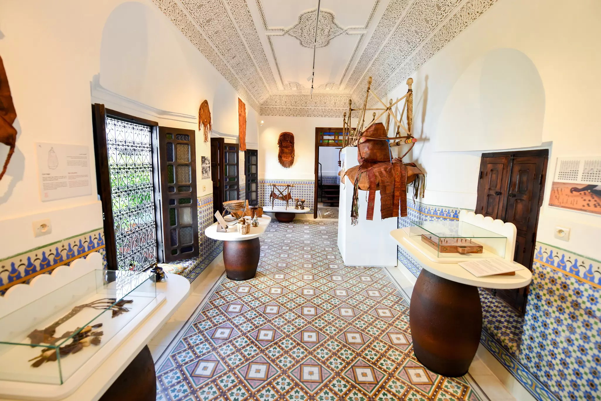 Objects displayed in cases in a room with white walls and a patterned tiled floor.