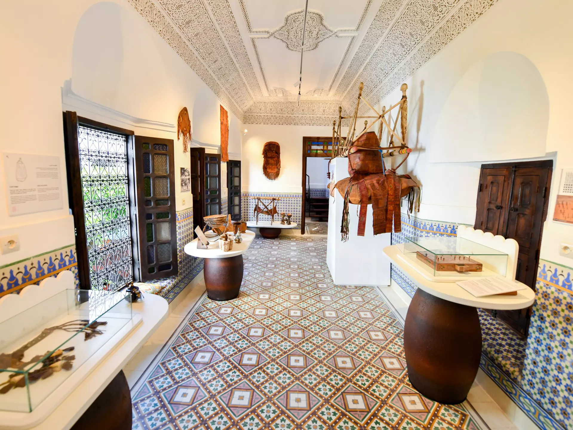 Objects displayed in cases in a room with white walls and a patterned tiled floor.